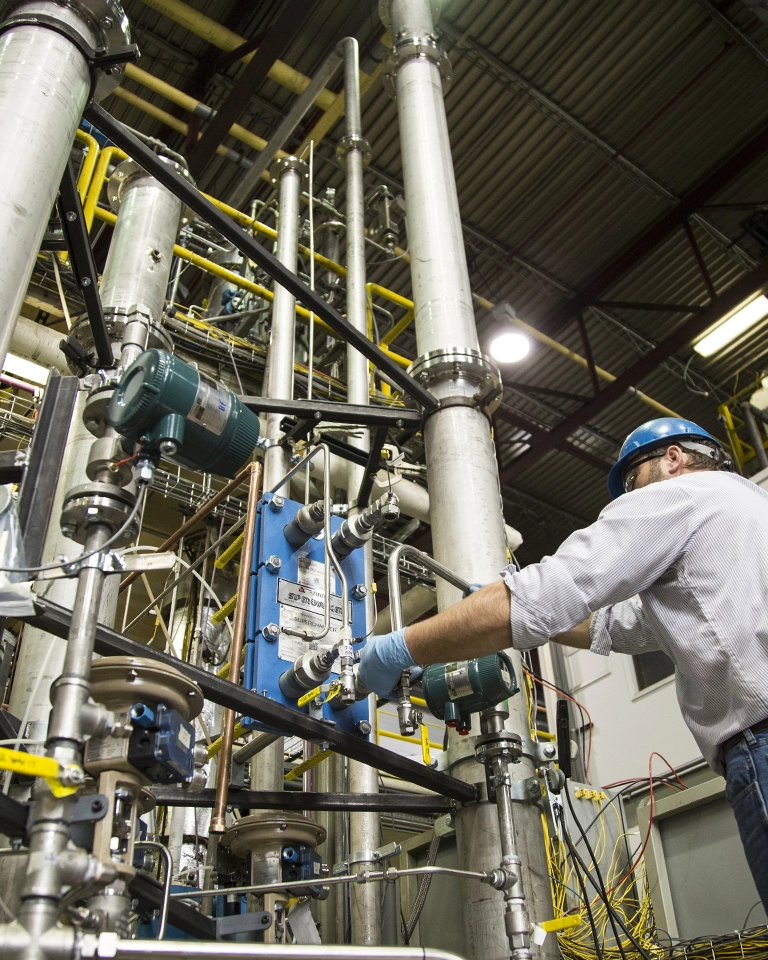 man in hard hat adjusting large equipment with pipes