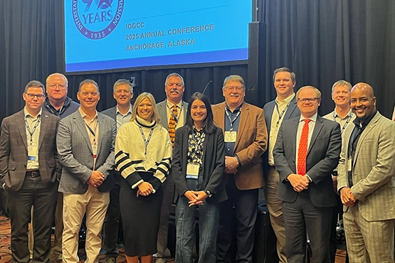 Group of conference attendees pose for a photo in front of a stge