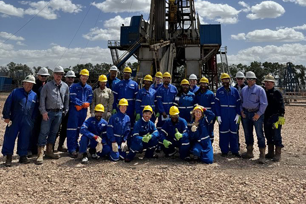 A group of interns wearing blue jumpsuits and yellow hard hats
