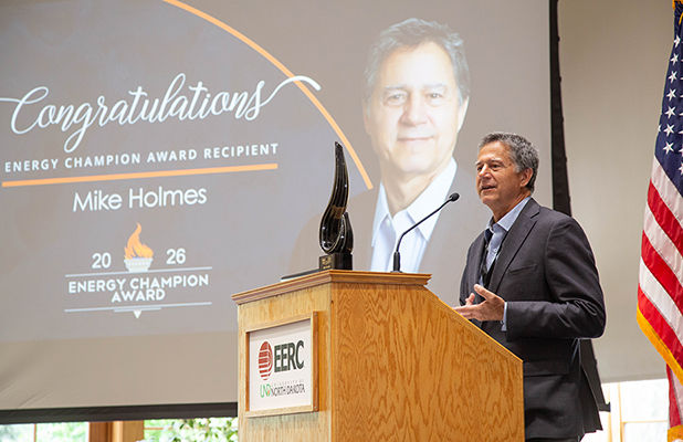 Mike stands at a podium and addresses a crowd. The Energy Champion award rests atop the podium.